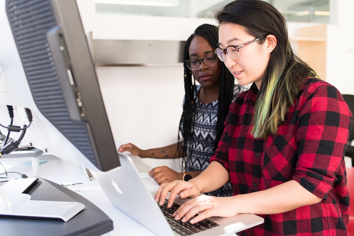 Two colleagues working through a problem at a computer